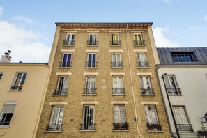 A multi-story building with a brick facade, multiple windows with shutters, and balconies with metal railings. - Spacious Apartment 2ch/6p - Boulogne-billancourt (Boulogne-Billancourt)