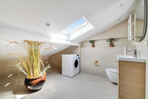 A modern bathroom with a skylight, a washing machine, a toilet, and a sink. - Spacious Apartment 2ch/6p - Boulogne-billancourt (Boulogne-Billancourt)