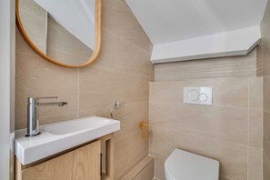Un baño con un lavamanos blanco, un espejo y un inodoro.