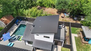 Una casa moderna con piscina, terraza y patio trasero cercado.