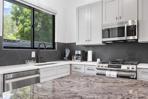 A modern kitchen with a large window, stainless steel appliances, and a marble countertop. - Cozy City Retreat with Apartment, 4 bedroom, 3.5 bath, large outside pool & spa (Austin)