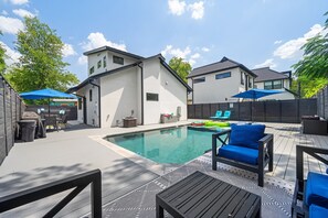Un jardin avec une piscine, du mobilier d’extérieur et un patio couvert.