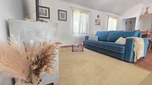 A living room with a blue sofa, a white cabinet, and a vase with dried plants. - The Haven of Happiness (Fataga)