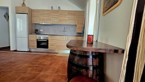 A kitchen with wooden cabinets, a white refrigerator, and a built-in oven. - The Haven of Happiness (Fataga)