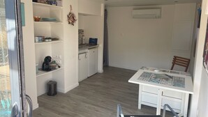 A compact kitchen with white cabinets, a coffee maker, and a small refrigerator.