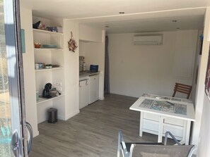 A compact kitchen with white cabinets, a coffee maker, and a small refrigerator.