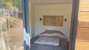 A bedroom with a bed, a wall-mounted artwork, and a wooden floor.