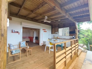 A wooden deck with a dining area, a kitchen, and a view of the outdoors. - Flaming Ti (Deshaies)