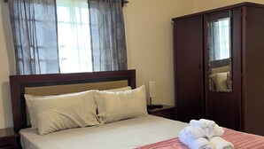 Quarto de hotel com cama, guarda-roupa, espelho e ar condicionado.