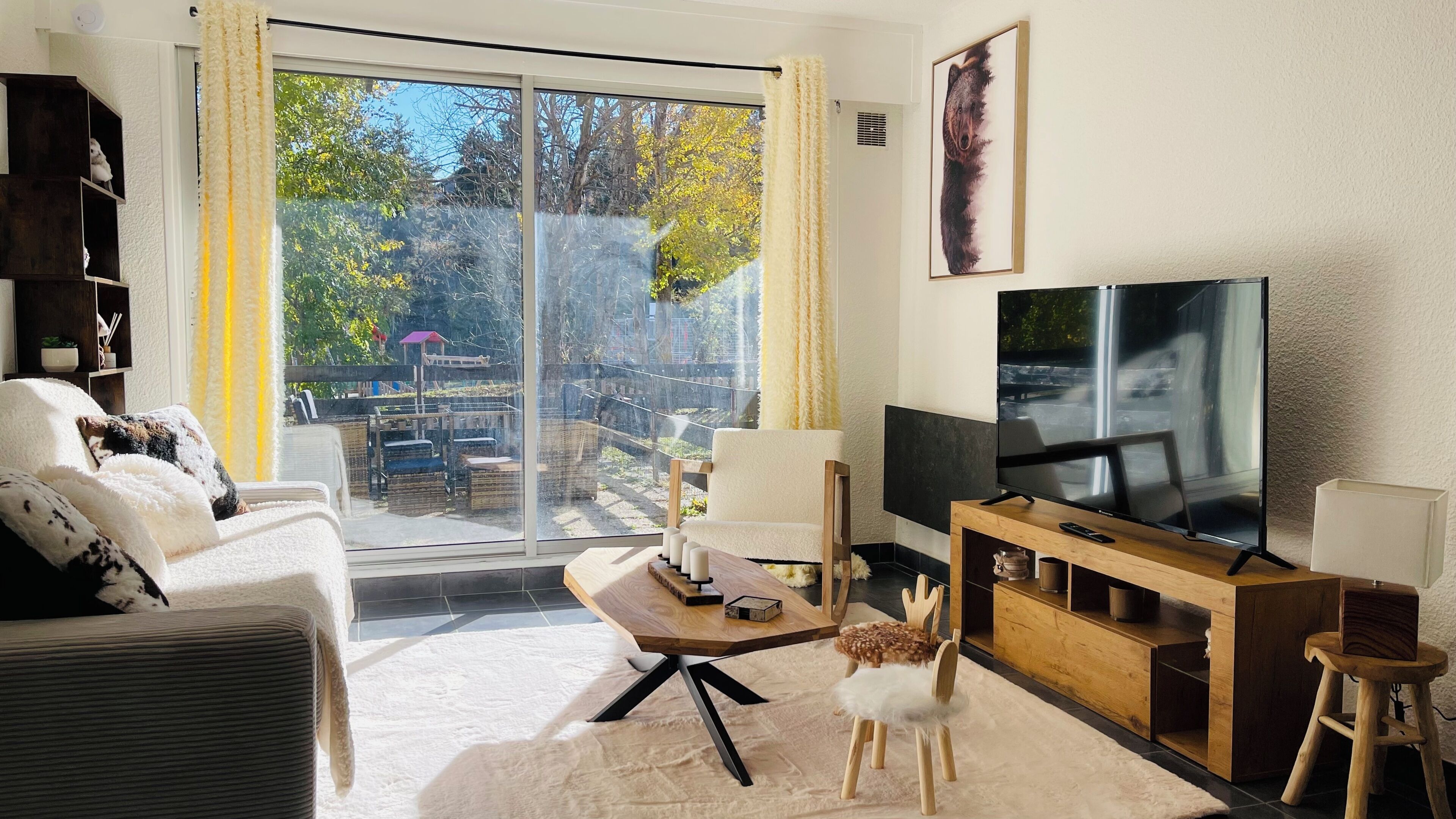 A living room with a sofa, a coffee table, a TV, and a view of the outdoors.