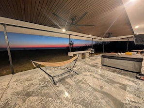 An outdoor patio with a hammock, a bench, and a small table with a cushion.