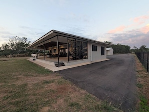 A modern building with a covered patio area, a flat roof, and a paved driveway.