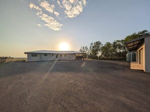 Un bâtiment doté d’un toit plat, d’un espace de stationnement couvert et surplombant un ciel dégagé.