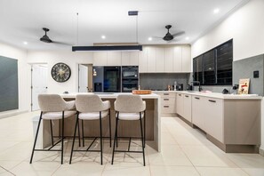 Une cuisine moderne dotée d’un îlot central, de tabourets de bar et d’une grande fenêtre.
