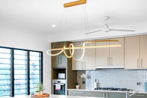 Una cocina moderna con iluminación colgante, ventilador de techo y un ventanal grande.