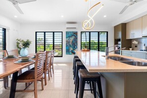 Una cocina moderna con una isla central, taburetes de bar y un comedor con sillas de madera.