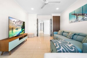 Ein modernes Wohnzimmer mit Flachbildfernseher, einer Couch und einem Bild an der Wand.