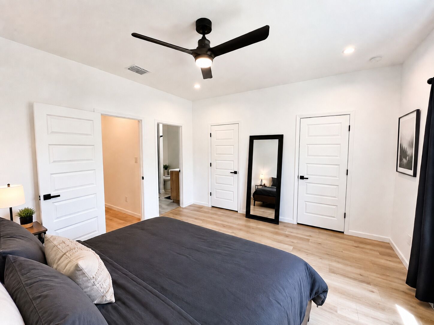 A bedroom with a bed, a ceiling fan, and white doors.