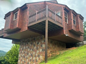 Eine mehrstöckige Holzhütte mit steinernen Fundamenten, einem Balkon und einer Steinmauer.