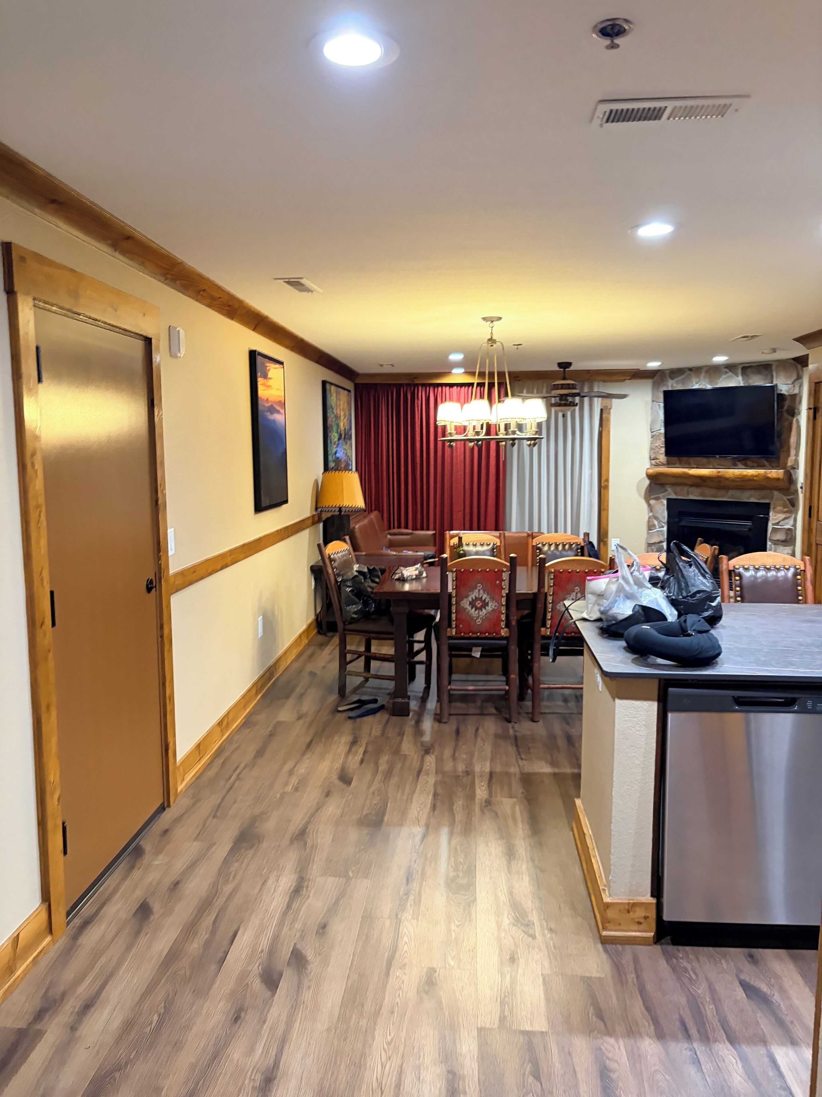 Ein Hotelzimmer mit Holzboden, einem Essbereich mit Tisch und Stühlen, einem an einer Steinwand befestigten Fernseher und einem eingebauten Geschirrspüler.