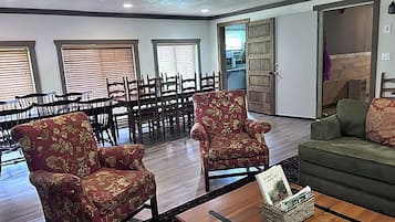A spacious room with a dining area, two armchairs, a sofa, and a coffee table.