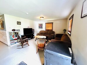 A living room with a television, bookshelves, a rocking chair, and a sofa.