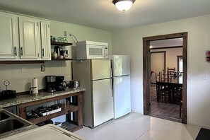 A kitchen with white cabinets, a microwave, a refrigerator, a coffee maker, and a sink. - Serene 6-bedroom hotel suites with AC in Equinunk (Equinunk)
