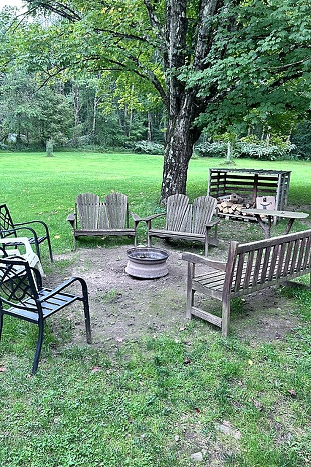 Un espace extérieur aménagé avec des chaises Adirondack et un foyer.