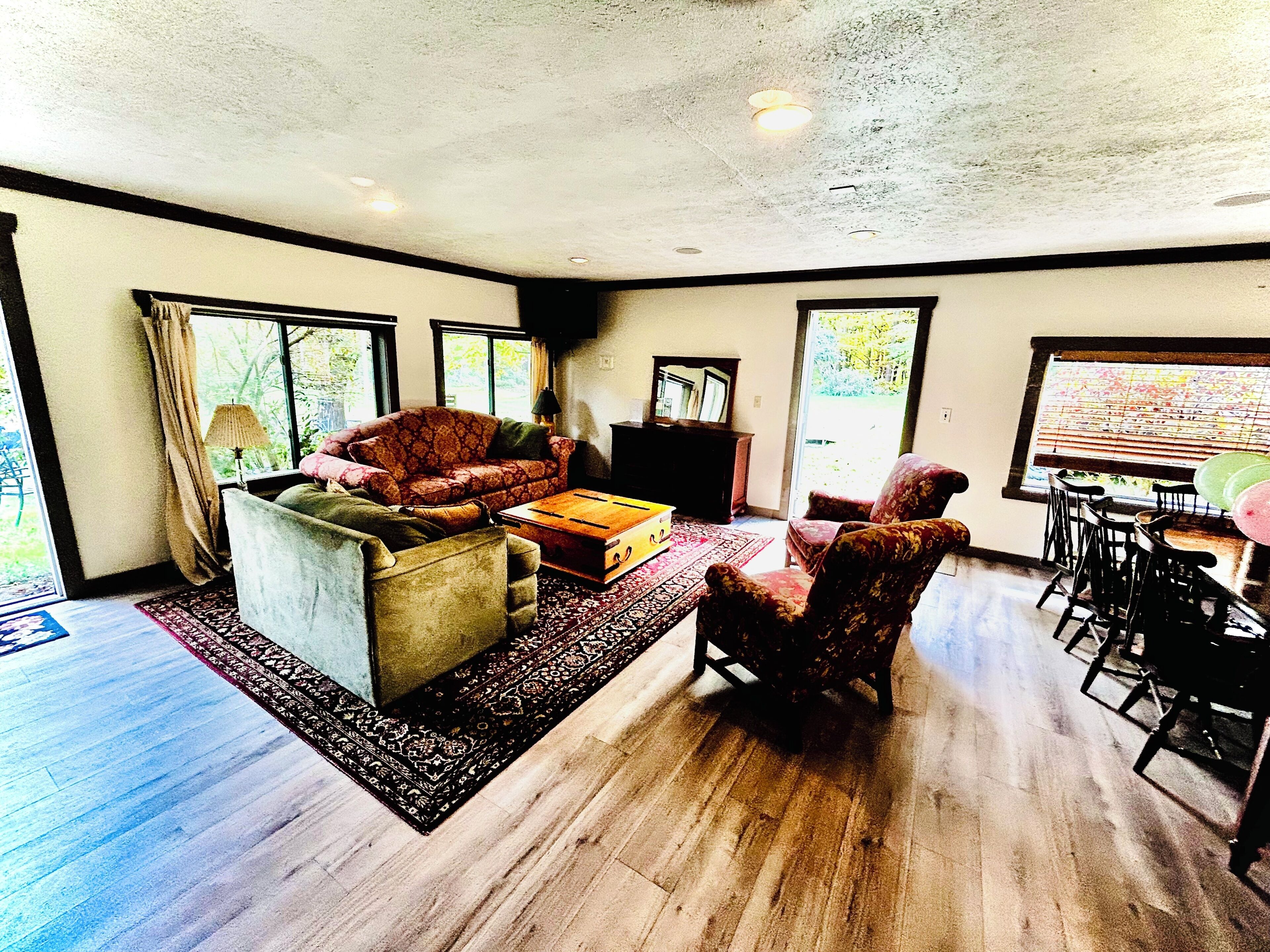 A spacious living room with a sofa, armchairs, a coffee table, and a dining area with chairs.