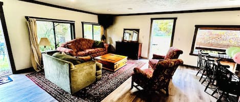 A spacious living room with a sofa, armchairs, a coffee table, and a dining area with chairs.