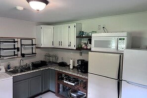A kitchen with white cabinets, a microwave, a coffee maker, and a sink.