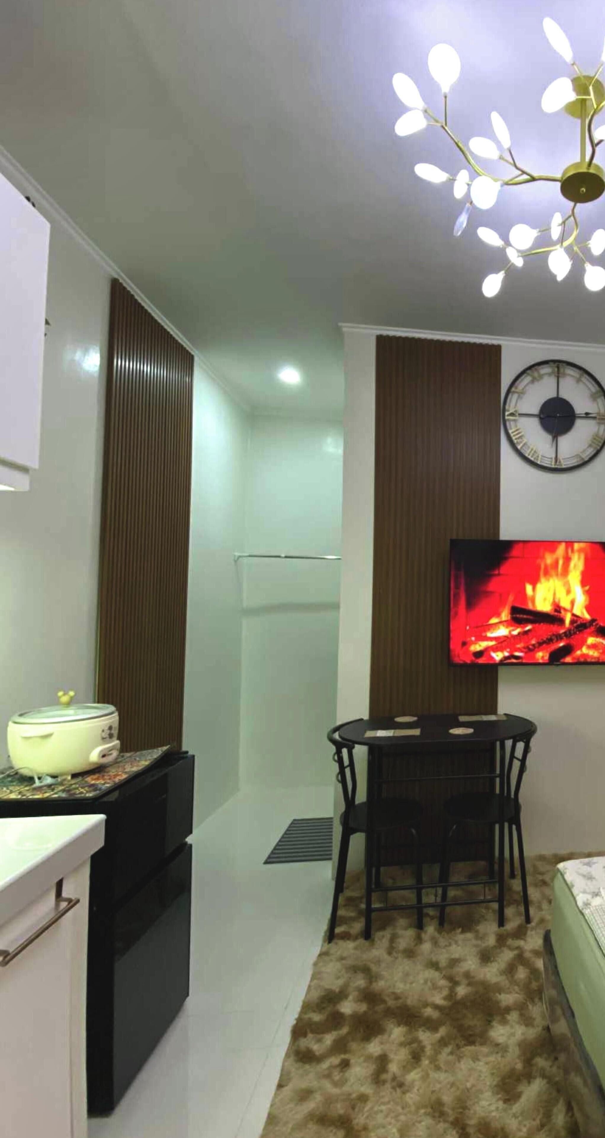 Un espacio habitable compacto con kitchenette, zona de comedor, televisor de pantalla plana y lámpara en el techo.