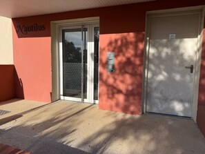 A building with a red exterior, a glass door, and a white door. - Comfortable one-bedroom apartment in La Londe with a terrace and parking – Argentière Beach is a 15-minute walk away (La Londe-les-Maures)