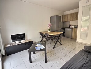 A modern living space with a flat-screen TV, a dining table with chairs, a kitchen area, and a sofa. - Comfortable one-bedroom apartment in La Londe with a terrace and parking – Argentière Beach is a 15-minute walk away (La Londe-les-Maures)