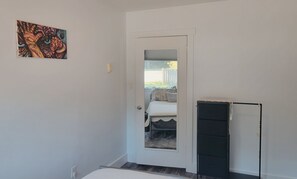 A room with a bed, a door leading to a balcony, and a black filing cabinet.
