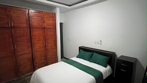 Ein Schlafzimmer mit Bett, Kleiderschrank und Schreibtisch.