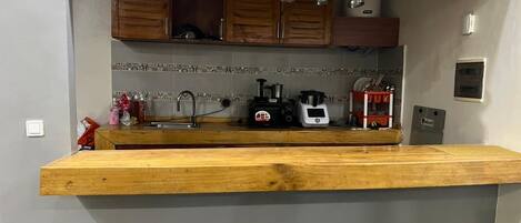 A kitchen with wooden cabinets, a countertop, a sink, and two stools.