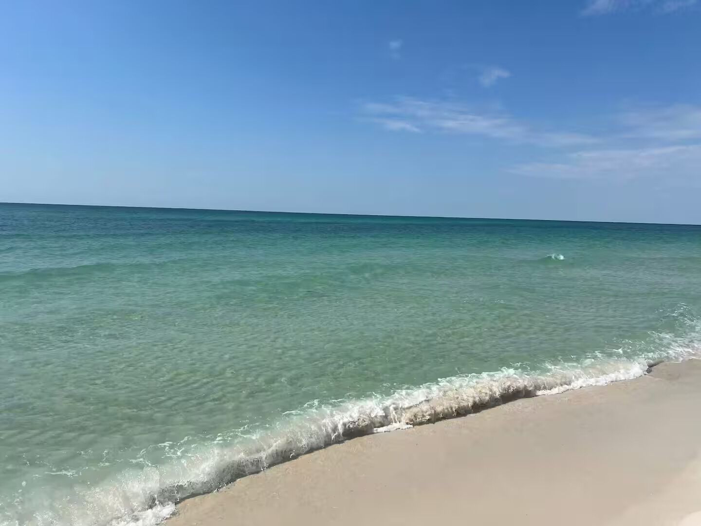 A beach with clear turquoise water and a sandy shore.
