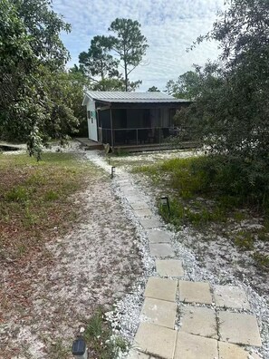 A pathway leading to a small building with a metal roof, surrounded by dense foliage. - Last minute cancellation. September 6-11th great weather and rates! Zero crowds (Gulf Shores)