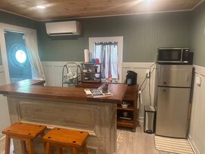 A compact kitchen with a wooden island, a stainless steel refrigerator, and a microwave. - The weather will shine in October and November. Best beach time of the year. (Gulf Shores)