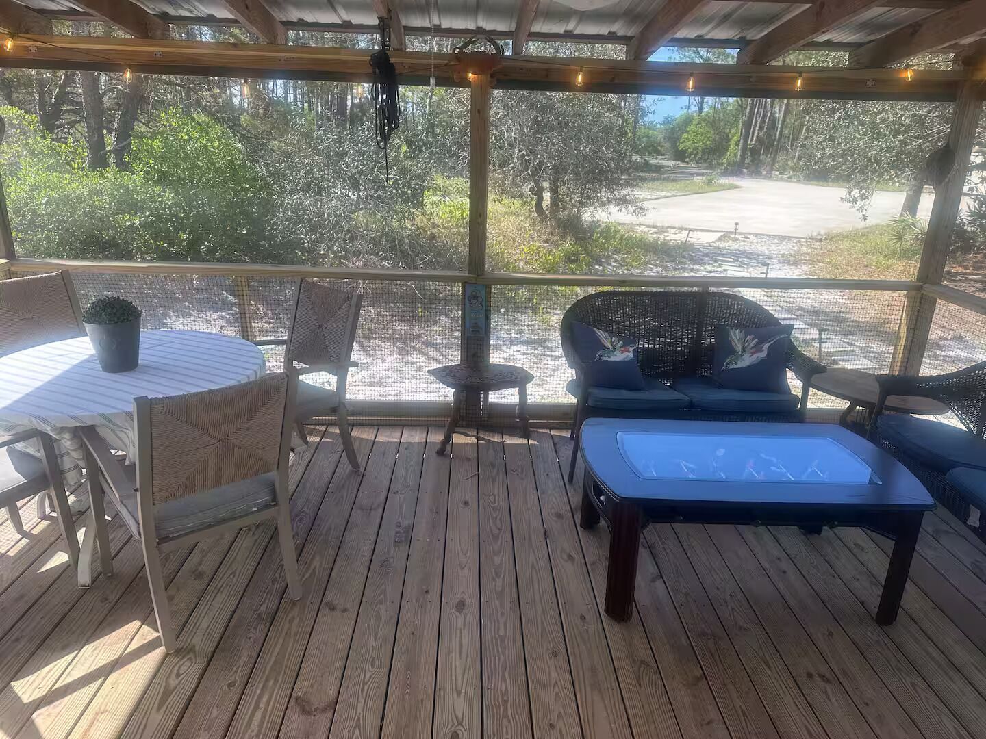 A covered outdoor seating area with a table, chairs, and a bench.