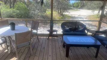 A covered outdoor seating area with a table, chairs, and a bench.