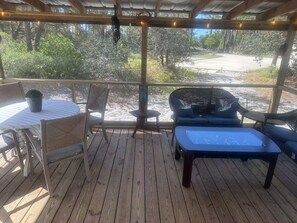 A covered outdoor seating area with a table, chairs, and a bench. - The weather will shine in October and November. Best beach time of the year. (Gulf Shores)