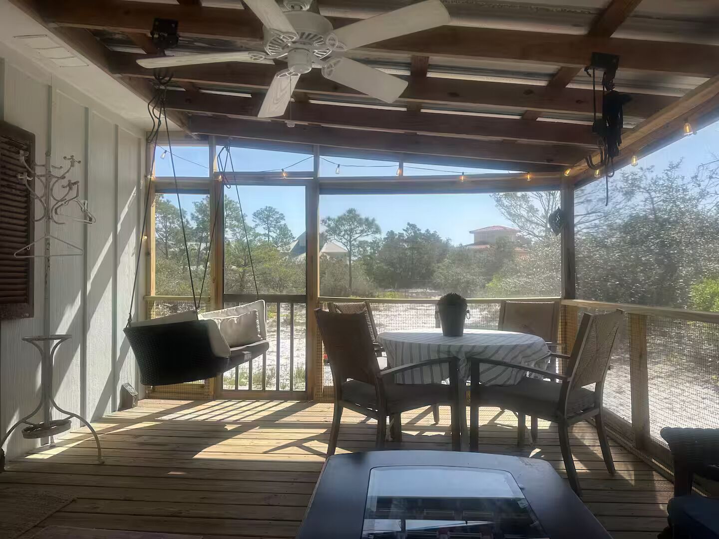 A covered outdoor area with a table and chairs, a ceiling fan, and a view of the surrounding landscape.