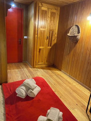A wooden room with a red door, a wooden wall, a red carpet, and a woven basket on the wall.