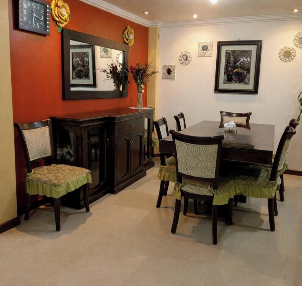 A dining area with a wooden table, chairs, a cabinet, and wall decorations.