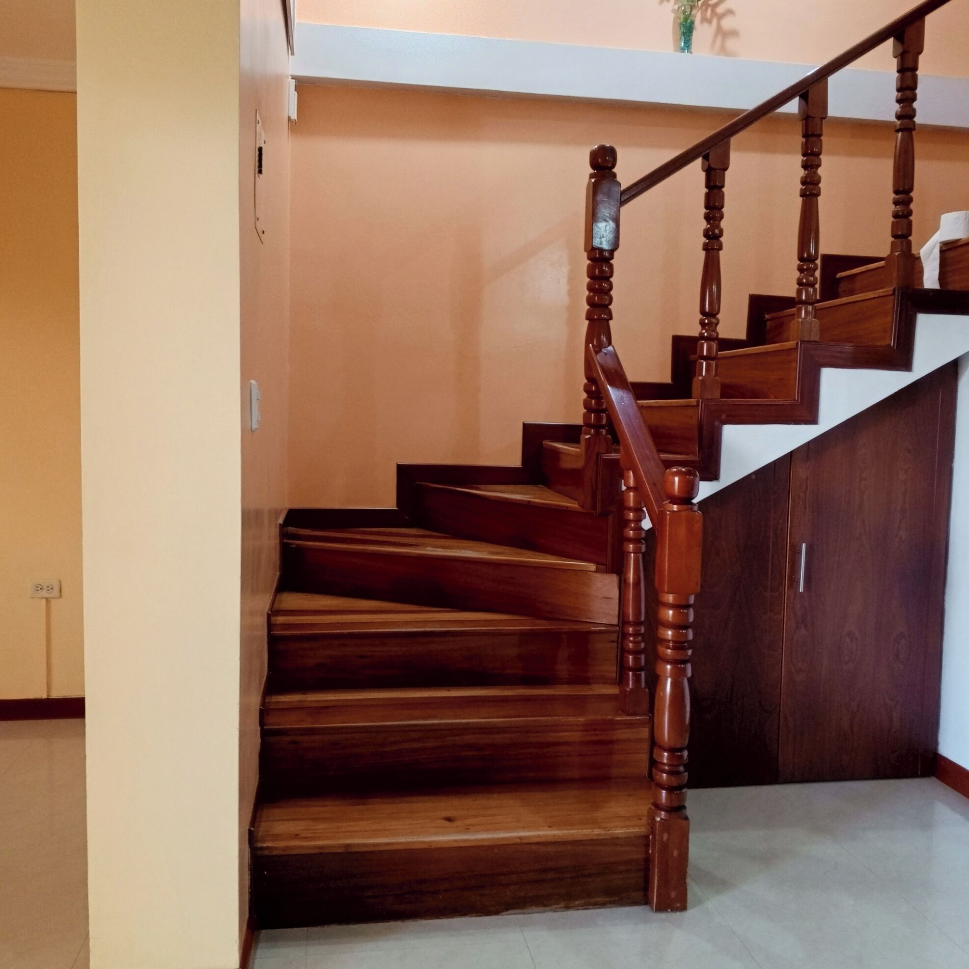 A wooden staircase with a handrail and a landing.