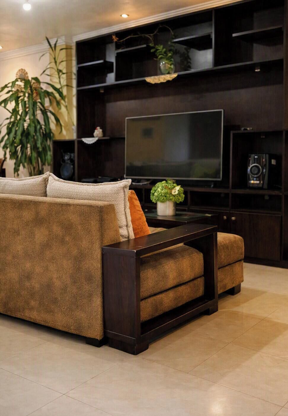 A modern living room with a dark wood entertainment unit, a flat-screen TV, a sofa, and a coffee table.