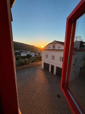 A courtyard with a cobblestone floor, a building with a tiled roof, and a clear sky. - A home you'll want to stay in, with a terrace overlooking the mountains and the village (Castelo de Vide)