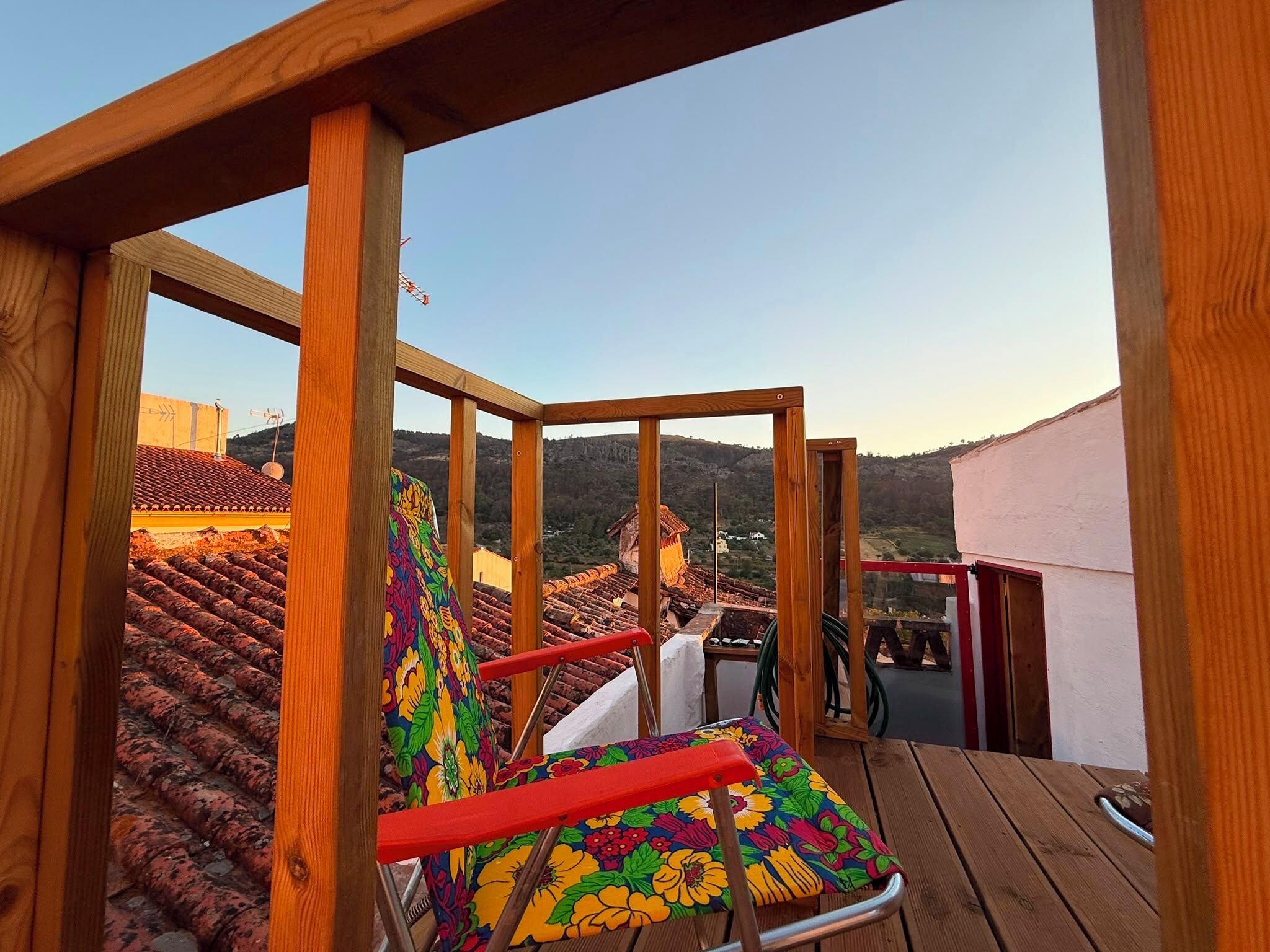A wooden deck with a view of terracotta-roofed buildings and hills in the background.